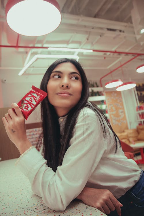 Woman in White Long Sleeve Shirt Holding a Chocolate