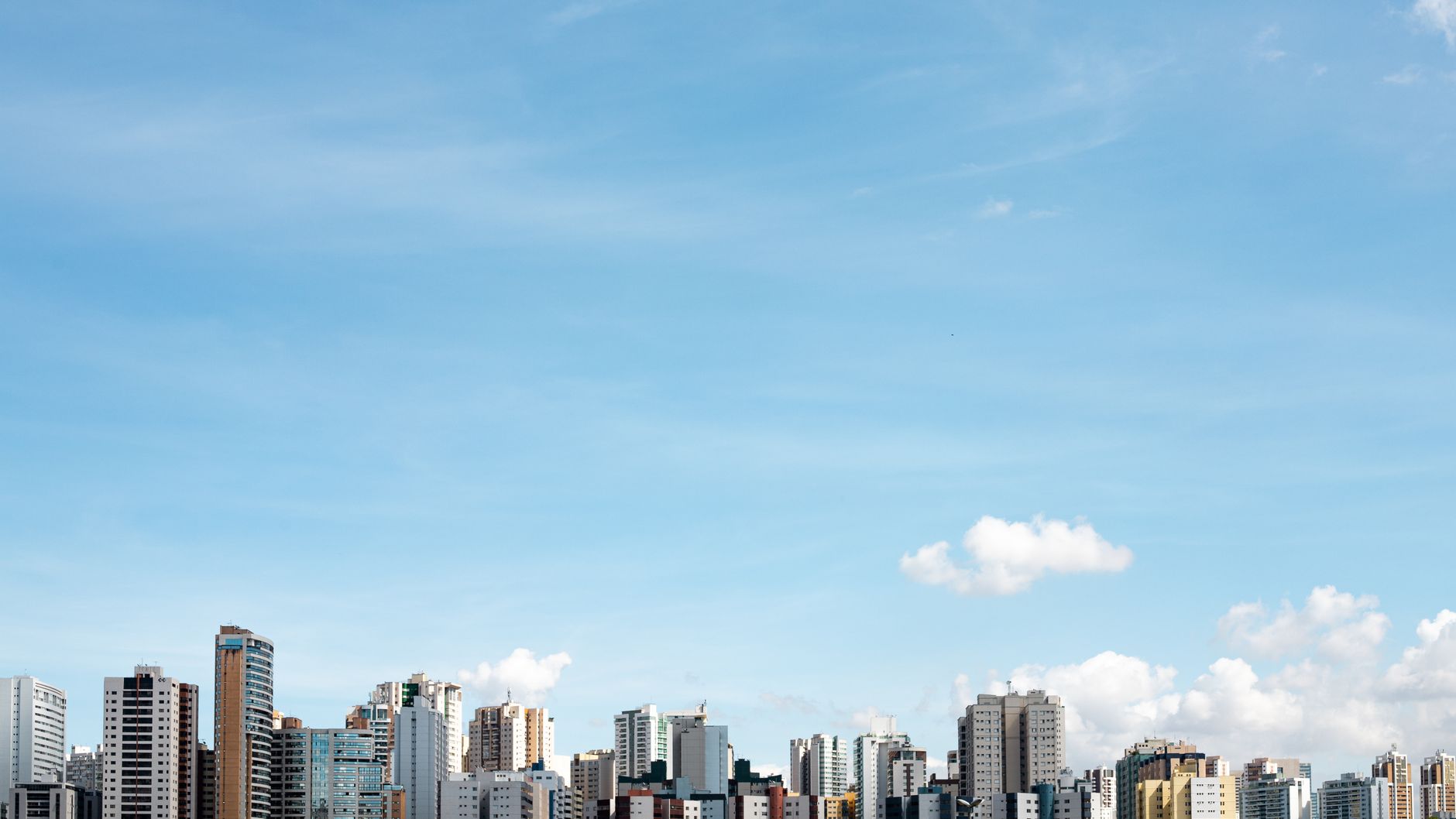 Distant view of Brasília skyline with bright blue sky and fluffy clouds.