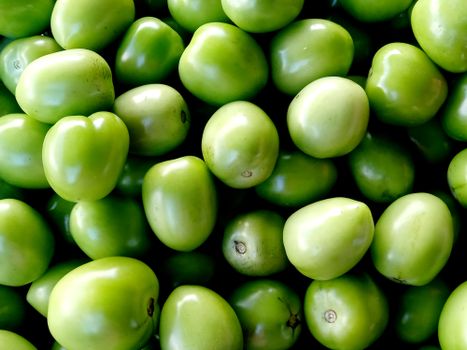 A vibrant close-up image of green tomatoes stacked together, showcasing their freshness and rich color.