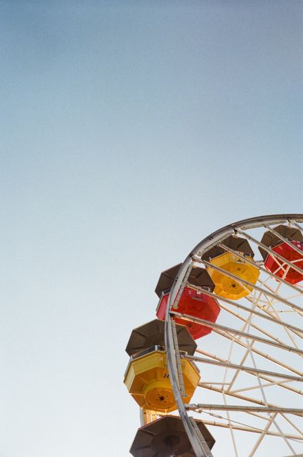 A vibrant Ferris wheel with colorful cabins set against a clear blue sky in Los Angeles.