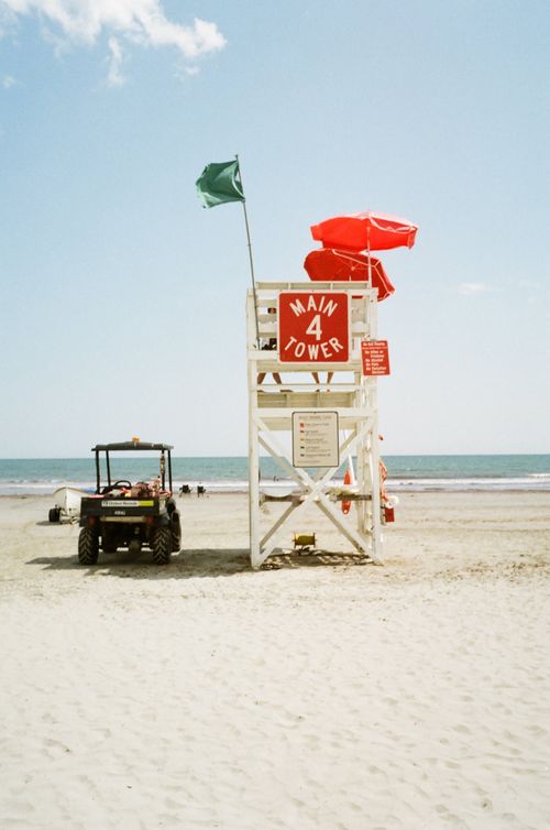 Free Lifeguard tower with red umbrellas and beach buggy on a sunny Rhode Island beach. Stock Photo