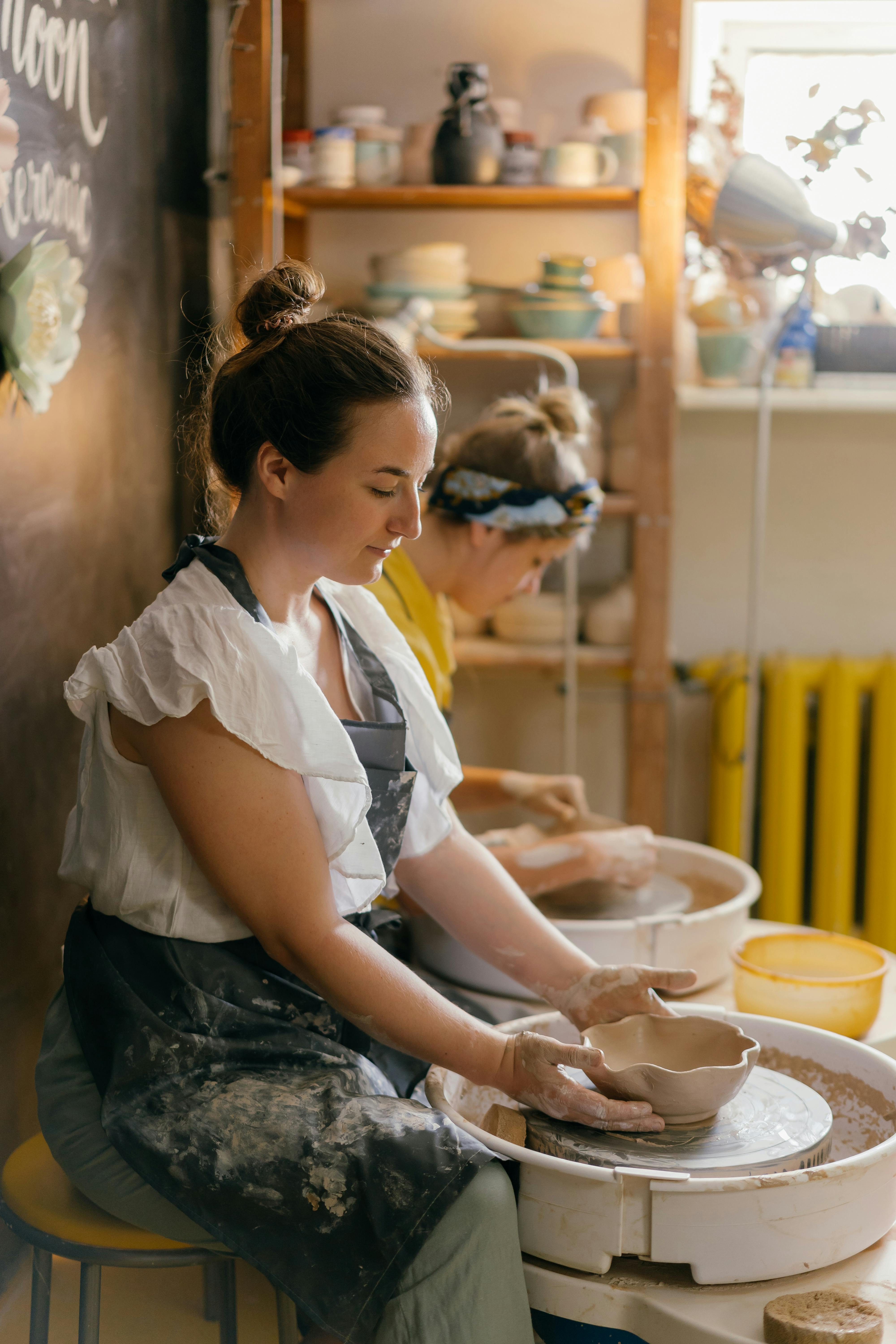 women forming dishes on potters wheels in workshop