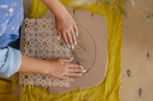 Woman Decorating Clay with Plant Twigs