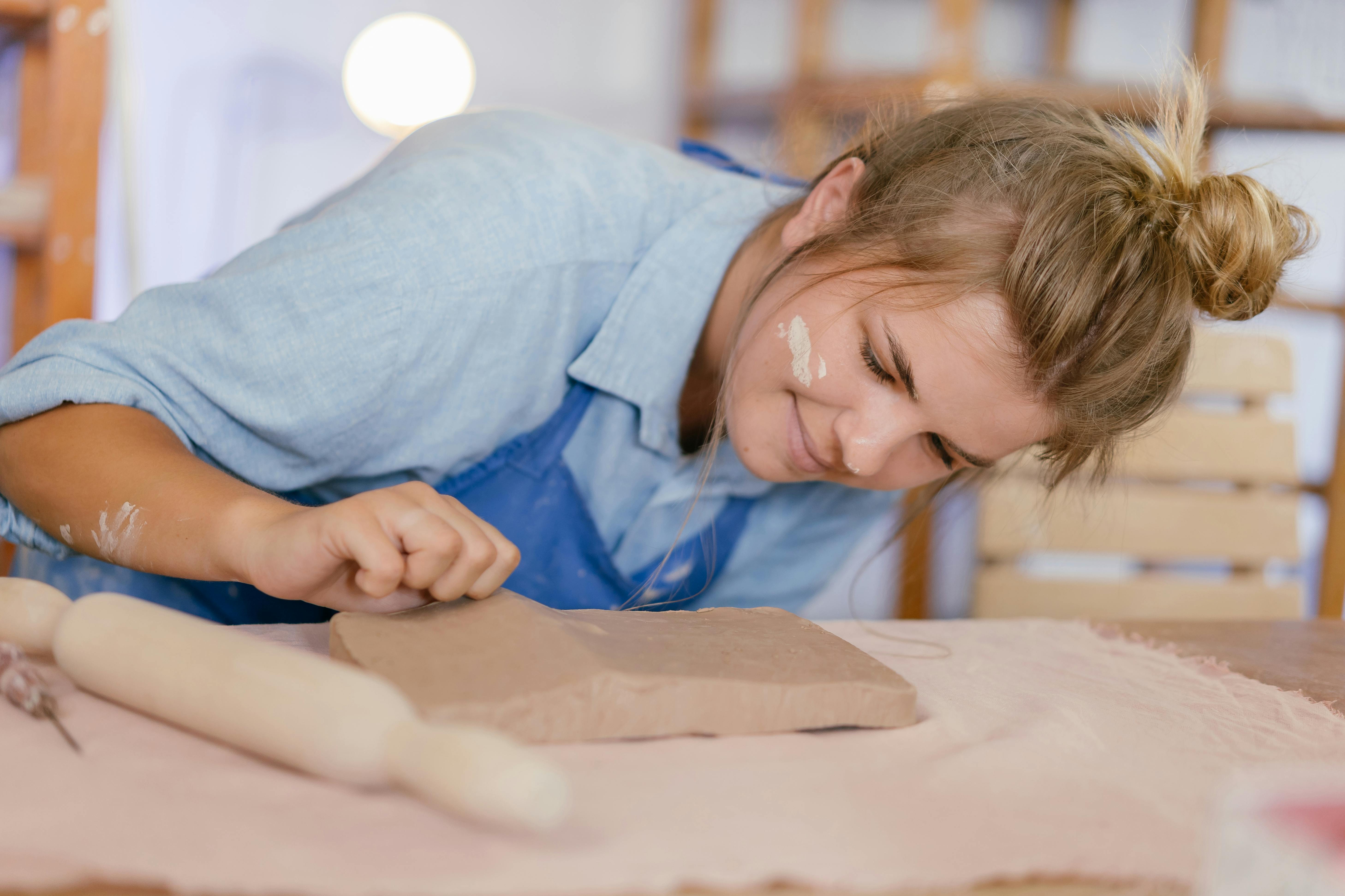 woman looking closely at clay on table