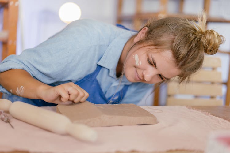 Woman Looking Closely At Clay On Table