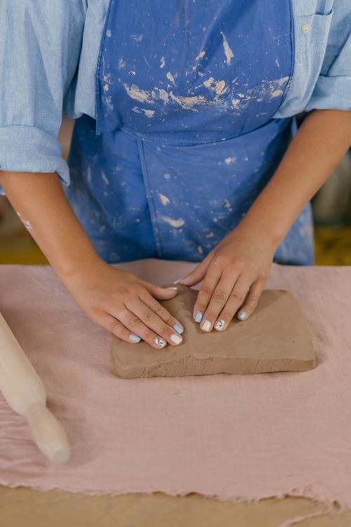 Free A woman working on a clay craft project, kneading clay on a table in an indoor studio. Stock Photo