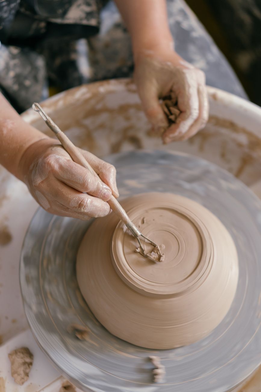 Hands expertly shaping a clay pot on a pottery wheel