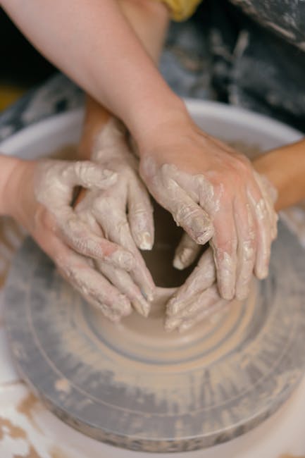 Close-up of hands molding clay on a pottery wheel, showcasing craftsmanship and artistic creation.
