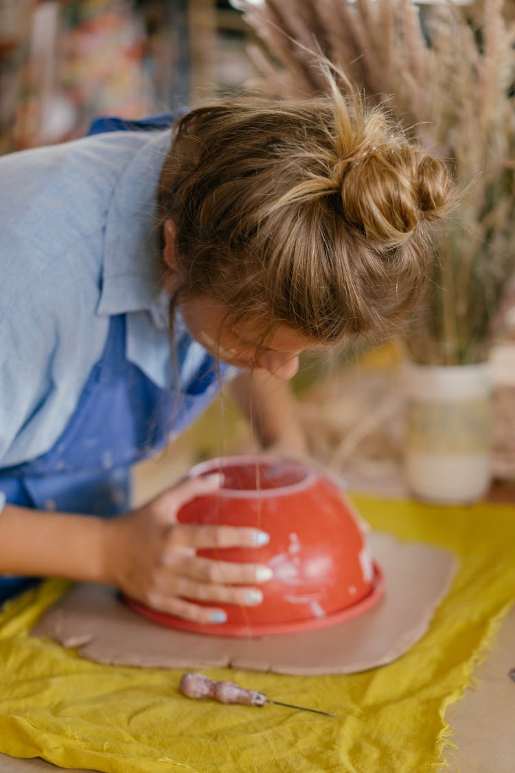 Woman In Blue Shirt Shaping A Clay Dough