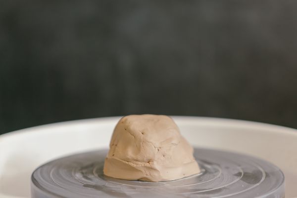 Wet clay centred on a potter’s wheel, photo by Mikhail Nilov on Pexels