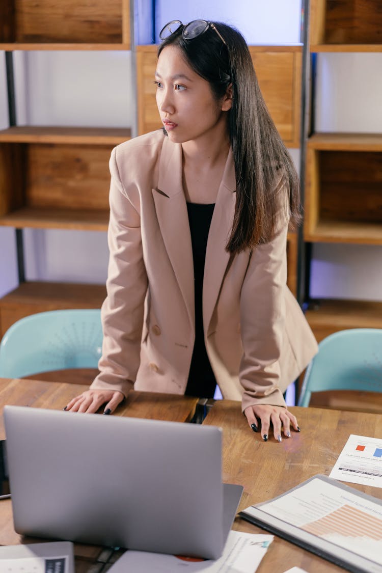 Woman In Business Attire Standing Facing A Laptop