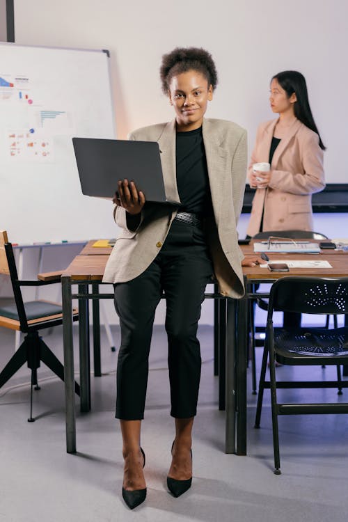 Woman in Black Pants Holding a Laptop
