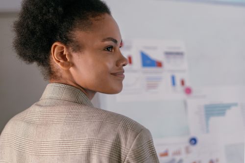 Free A confident businesswoman with curly hair smiling while presenting data charts in an office. Stock Photo