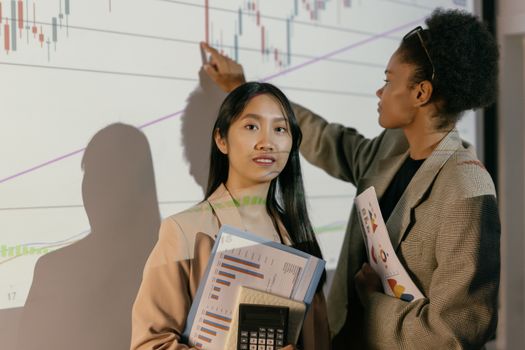 Two businesswomen analyze financial projections, showing leadership and teamwork.