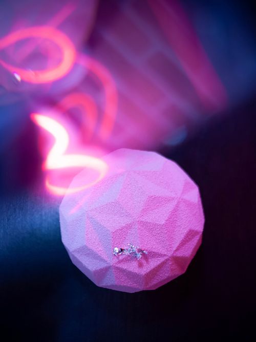 Free Pink geometric ball with glittery highlights under blurred neon lights. Stock Photo