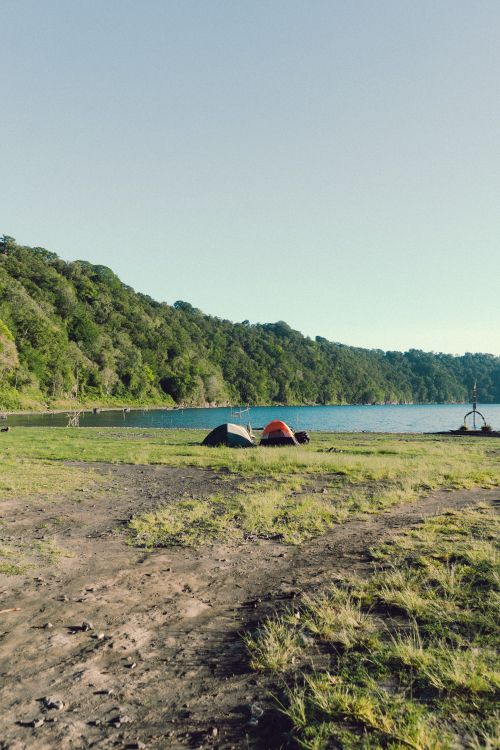 Free Peaceful camping scene by a clear lake with tents and lush greenery in Bali, Indonesia. Stock Photo