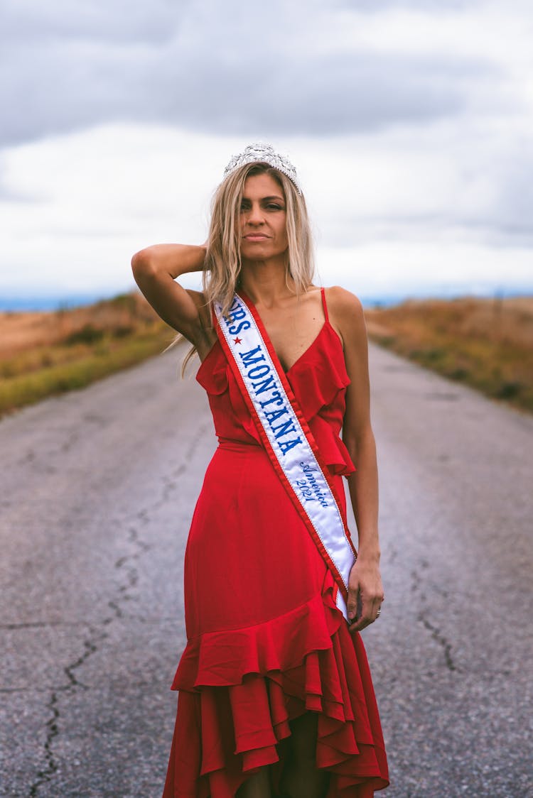 A Woman In A Red Dress Wearing A Sash