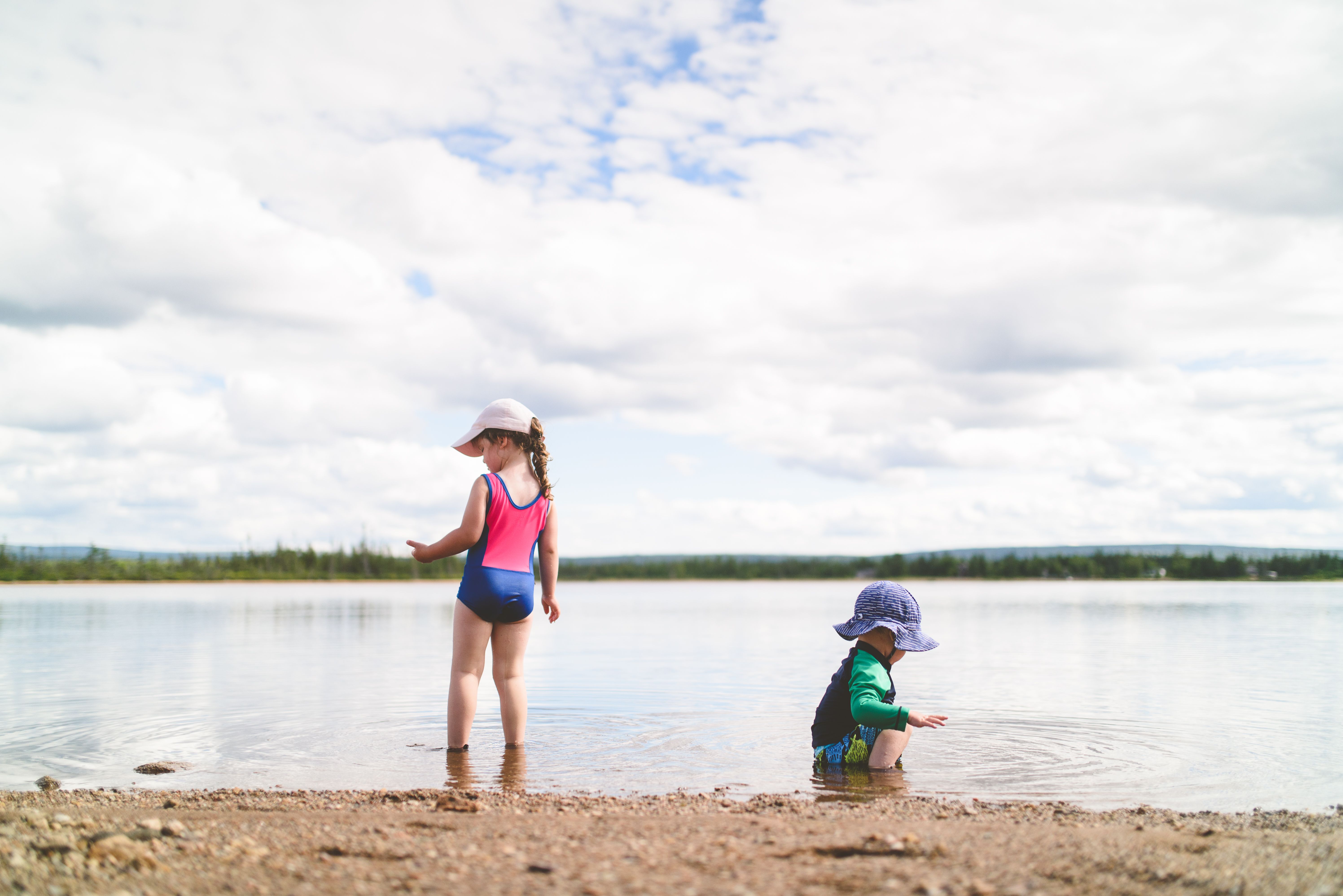 Two kids enjoy playing by the water at the beach under a cloudy sky. - Photo by Stephen Andrews on Pexels