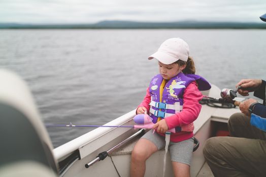A Young Girl Fishing while on a Motorboat