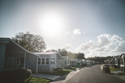 Quiet suburban street with houses, trees, and a clear blue sky. Perfect for real estate and lifestyle concepts.