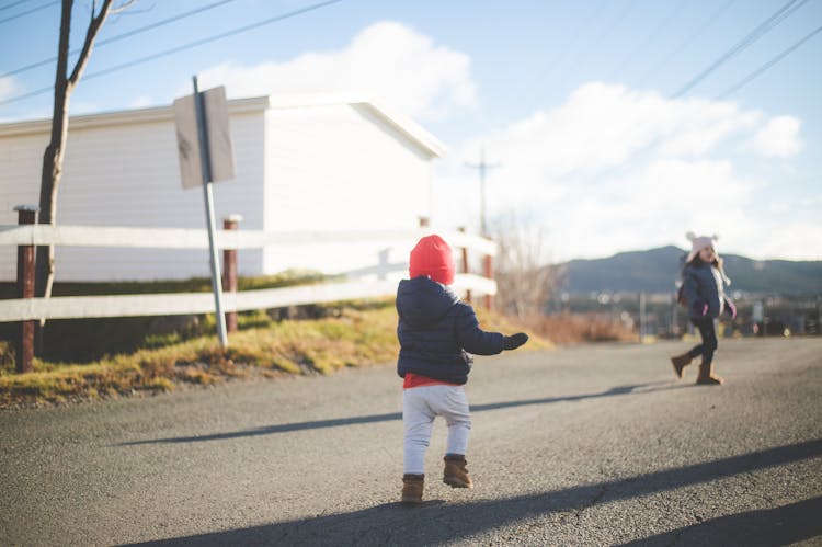 Kids Wearing Winter Clothes Running On The Road 