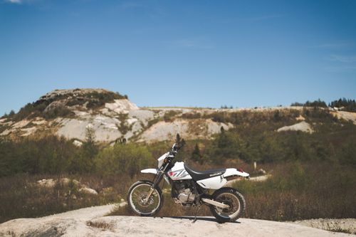 Free A lone motorcycle stands boldly in a rugged desert terrain, perfect for adventure sports. Stock Photo