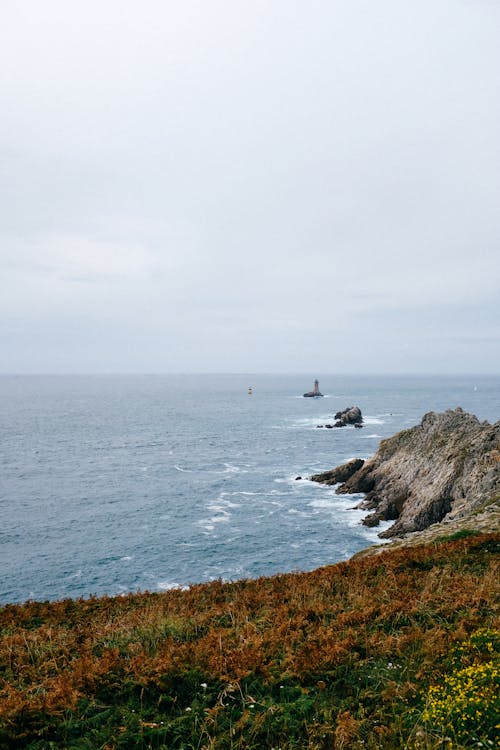 Gratis arkivbilde med bergformasjoner, gressfelt, hav