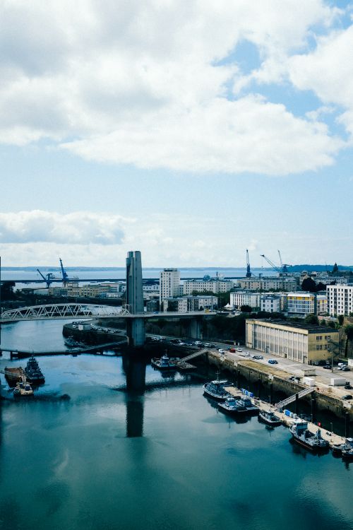 Free A vibrant urban cityscape with modern architecture and a bustling harbor under a cloudy sky. Stock Photo