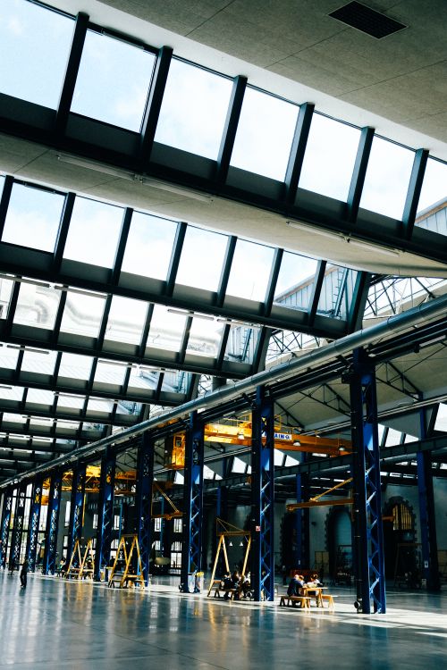 Free Spacious industrial interior with skylights, steel beams, and a bright atmosphere. Ideal for modern architecture and construction themes. Stock Photo