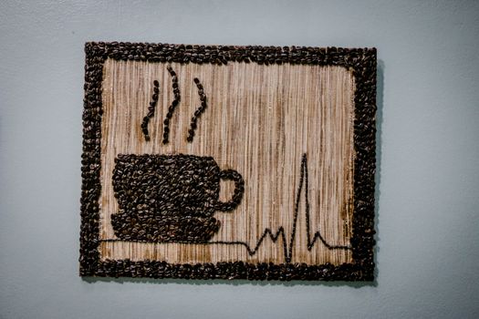 Unique wall decor featuring a coffee cup and heartbeat design made with coffee beans.