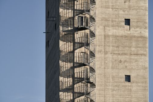 Free A striking view of a concrete building featuring a spiral metal staircase casting shadows. Stock Photo