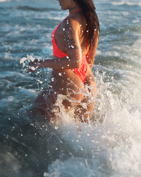 Woman in vibrant bikini enjoying the waves at Florianópolis beach.