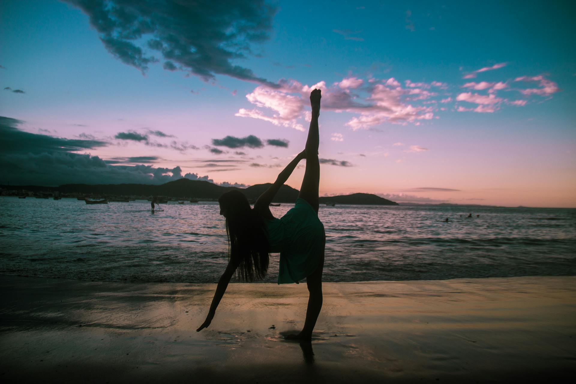 A woman performs a yoga pose on a Brazilian beach at sunset, capturing serenity and balance.