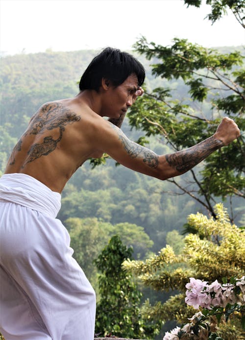 A Topless Man With Tattoos Doing a Fighting Pose