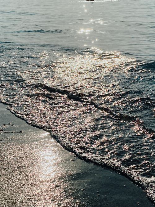 Free Capture the serene beauty of ocean waves glistening under the sunset. Stock Photo