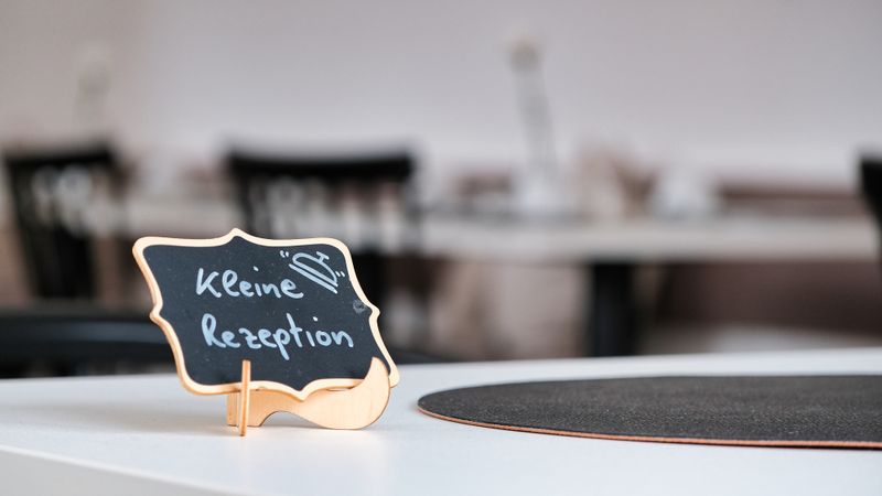 Chalkboard sign reading 'Kleine Rezeption' on a restaurant table, perfect for cozy dining ambiance.