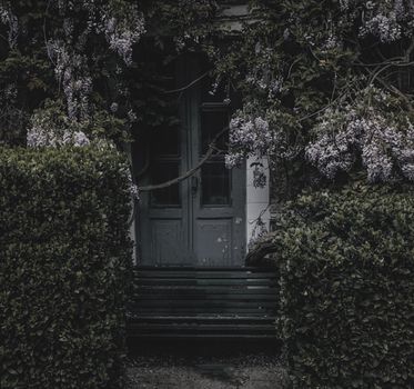 Mystical wooden door covered by climbing plants and flowers, creating an enchanted entrance.