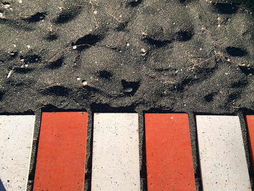 Red and White Metal Planks on Black Sand