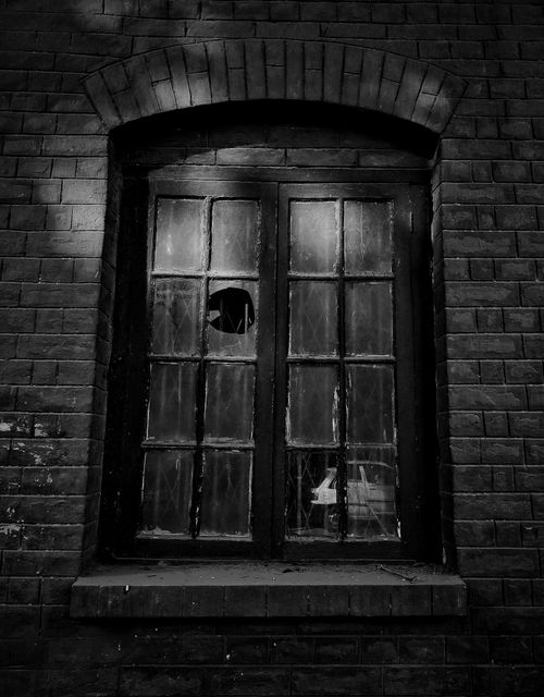 Free Black and white photo of a brick wall featuring a broken glass window, capturing a vintage atmosphere. Stock Photo