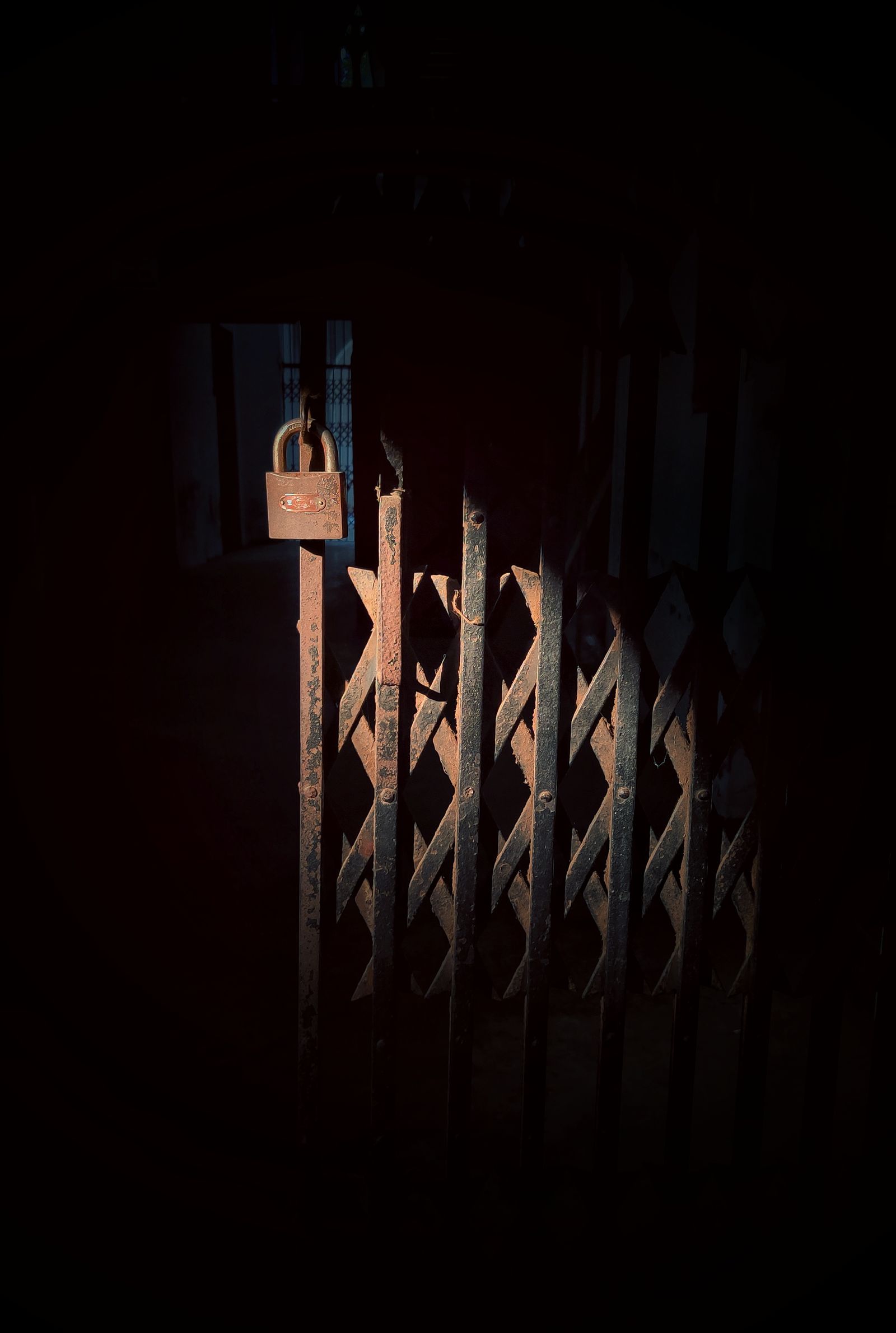 A rusty accordion gate secured with a padlock