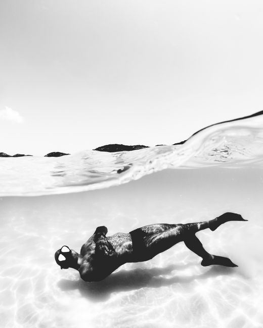 Black and white photo of a diver swimming underwater in Arraial do Cabo, Brazil.