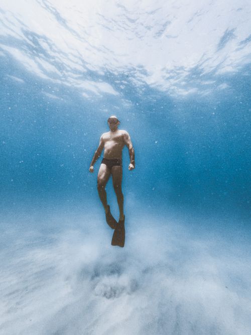 Free A man diving underwater in the pristine ocean waters of Arraial do Cabo, Brazil. Stock Photo