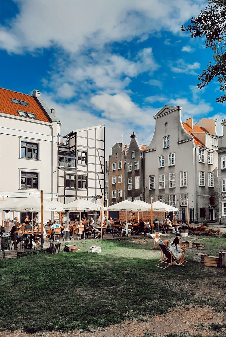 People Sitting Under Patio Umbrellas Outside A Restaurant 