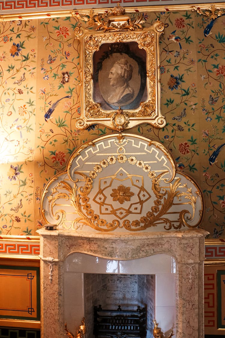 A Marble Fireplace With Floral Wallpaper