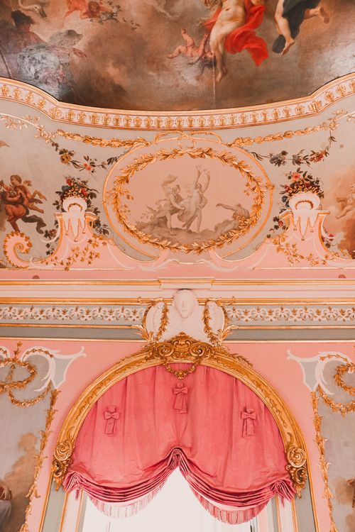 Free Elegant ornate ceiling with classical fresco art and rich decorations in gold and pink tones. Stock Photo