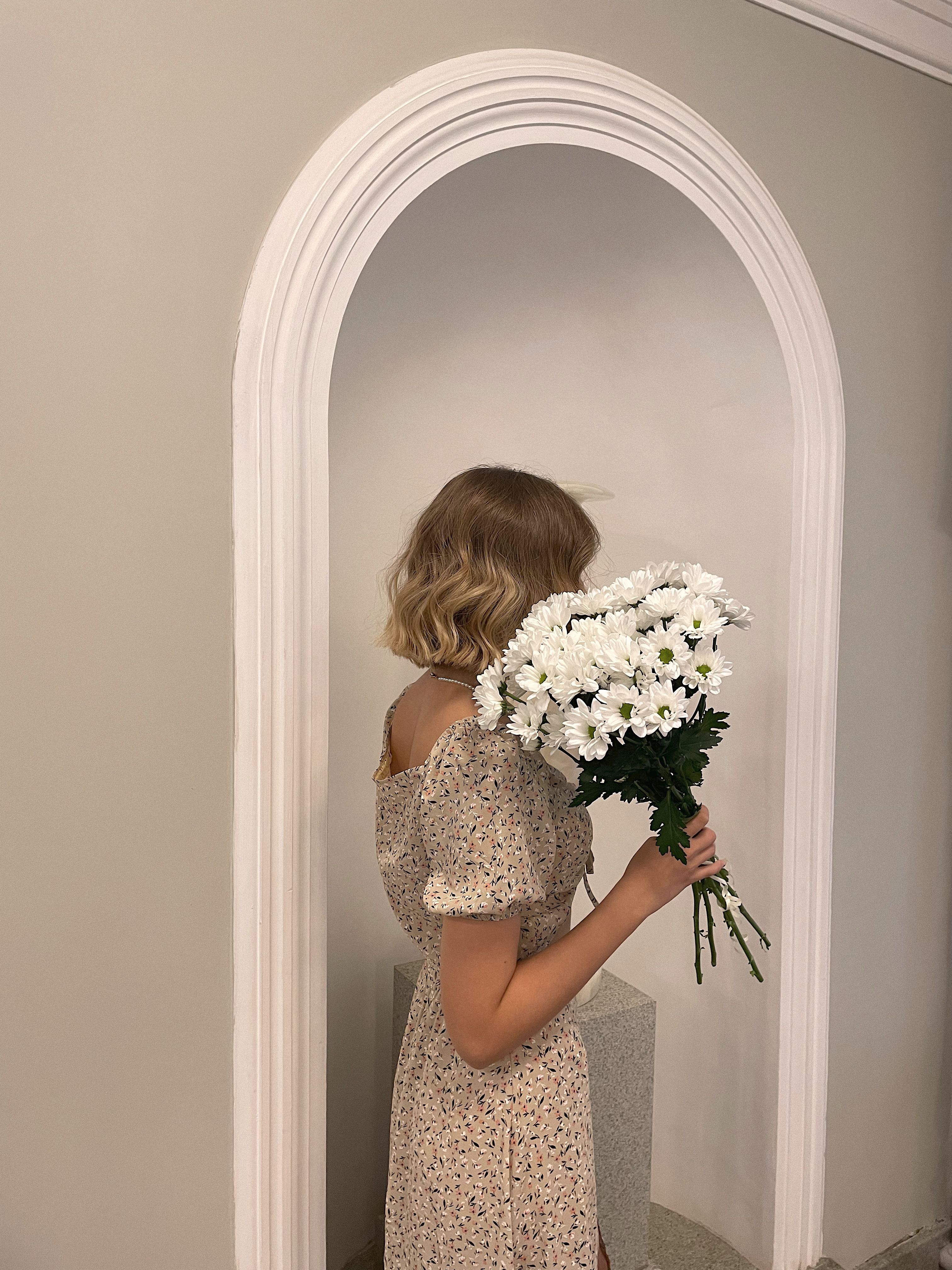A Woman in Floral Dress Holding a Bunch of White Flowers · Free Stock Photo
