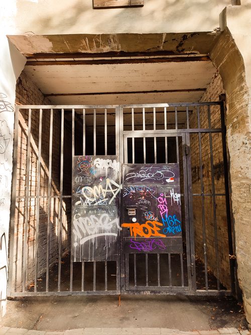Free Steel gate with vibrant graffiti on an abandoned building, creating an urban art scene. Stock Photo