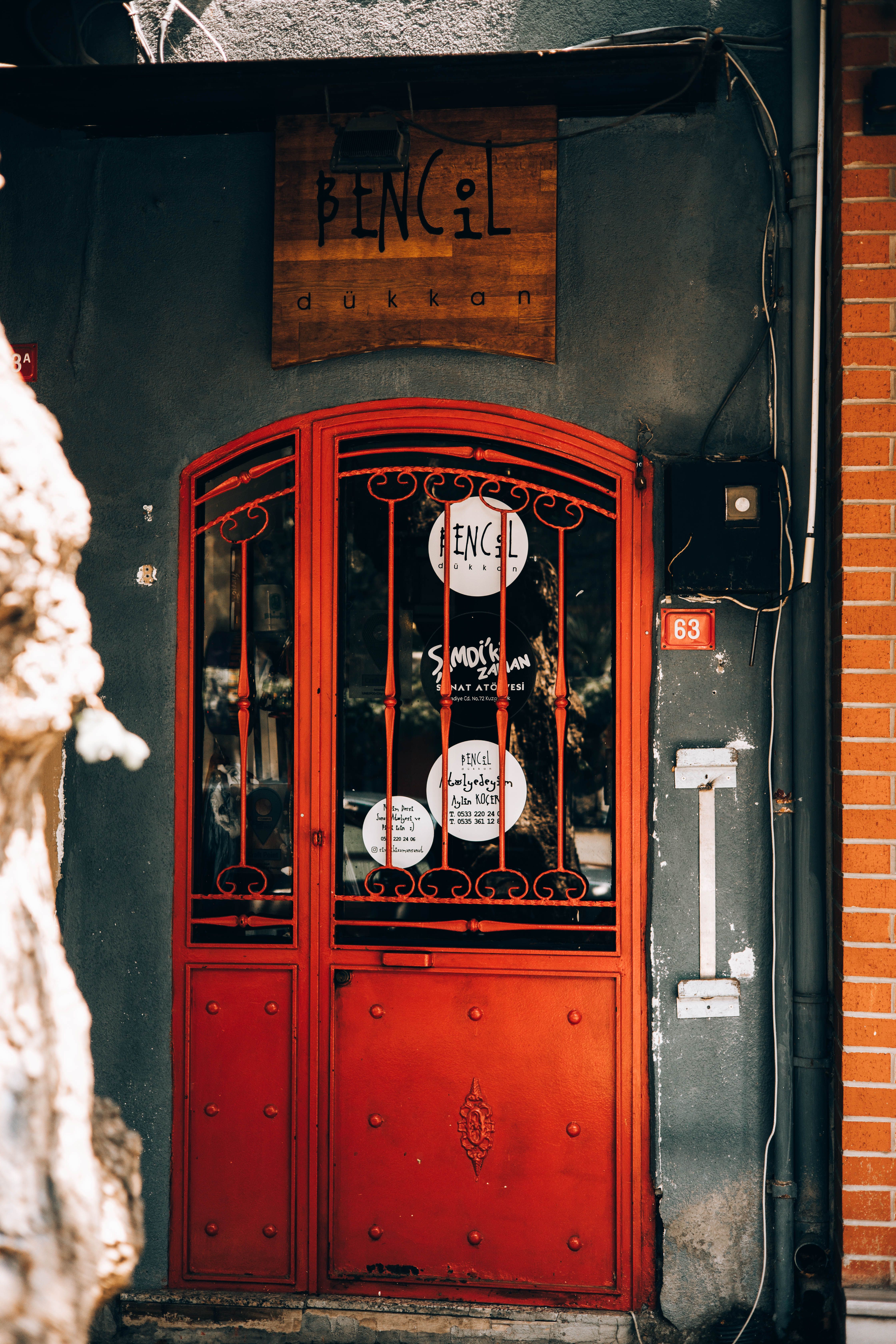 Red door of a boutique shop with vintage signage and decorative ironwork.
