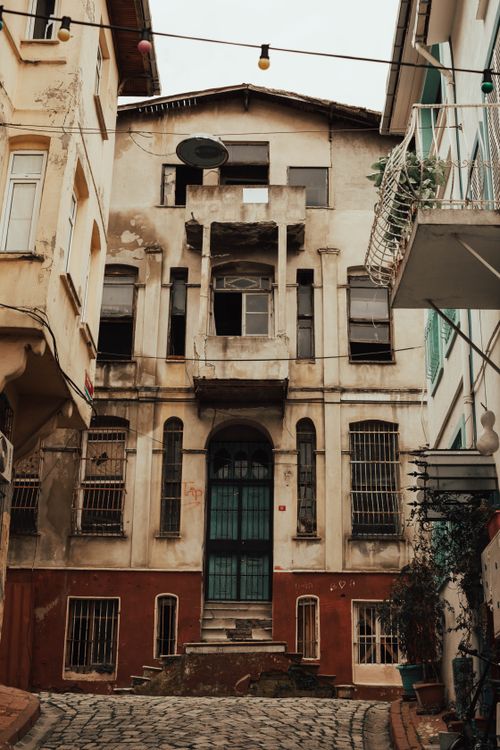Free A shabby, historic urban building with a stained facade and cobbled street. Stock Photo
