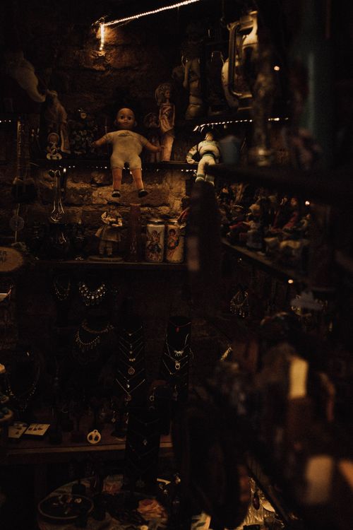 Free A dark, artistic display of vintage dolls, necklaces, and toys on shelves. Stock Photo